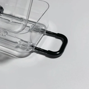 Close-up of a mini transparent luggage-style jewelry box with black carabiner clip