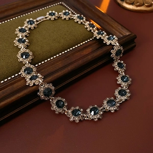 Détail d'un collier vintage doré avec fleurs serties de pierres précieuses bleu foncé