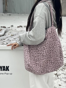 Pink leopard print suede tote bag carried by a model in a snowy outdoor scene
