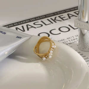 Vue macro d'une bague dorée avec perles et cristaux sur une assiette blanche