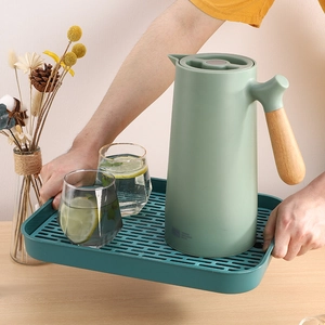 Carafe isotherme verte avec poignée en bois sur plateau d'égouttage assorti