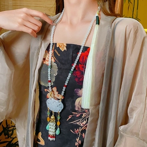 Detail of beaded tassel necklace with Ruyi jade pendant and golden bell accent