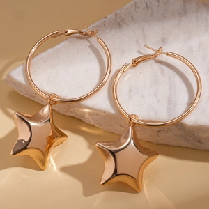 Macro shot of gold geometric hoop earrings with a star pendant on marble