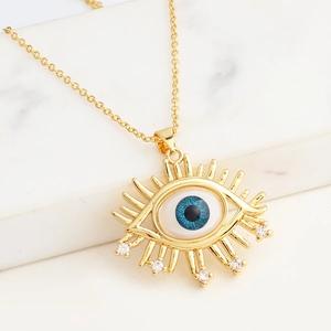 Makroaufnahme des goldenen Evil Eye Anhängers mit blauem Auge und funkelnden Kristallen