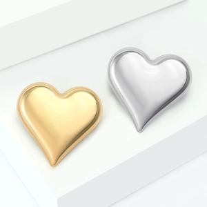Polished heart-shaped alloy brooches in gold and silver finish on a white stand