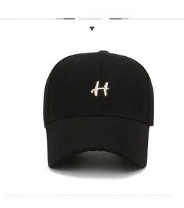 Close-up of beige H letter embroidery on black cotton canvas baseball cap