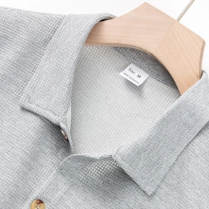 Detalle del cuello de camisa gris de punto de gofre con textura de tela suave