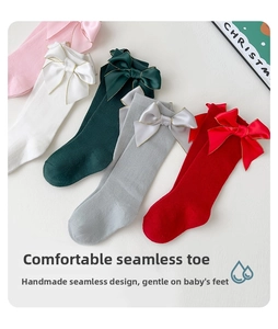 Détail de chaussettes hautes pour bébé avec nœud en satin doré et pointe sans couture