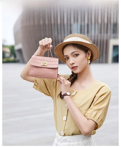 Detailed view of pink crocodile pattern handbag with metal twist lock and chain strap