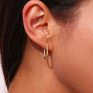 Minimalist oval hoop earrings in 18K gold plated stainless steel on a female model