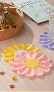 Close-up of daisy-shaped heat resistant silicone mat in pastel pink and yellow tones