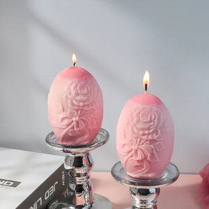 Detalle de vela de huevo rosa con relieve de rosas sobre un soporte de metal plateado