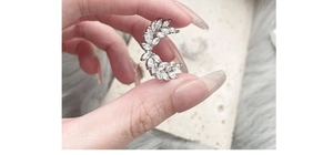 Detailed view of silver wheat spike earrings with sparkling zircon stones held by hand