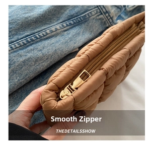 Detail of smooth gold zipper and caramel brown quilted puffer fabric on handbag
