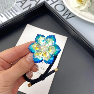 Detail shot of the crystal snow lotus hair tie showing blue gradient petals and elastic band