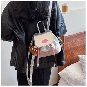 Silver metallic mini backpack with pink drawstrings and cute plush pendant on a model