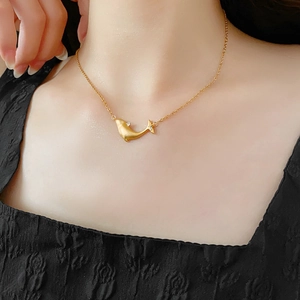 Close-up of golden whale pendant necklace with zircon stone worn by a model
