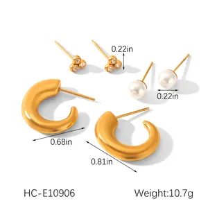 Detail of gold earrings set featuring pearl studs and chunky C-shaped metal hoops