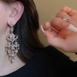 Close-up of long chandelier heart tassel earrings with sparkling rhinestones on model