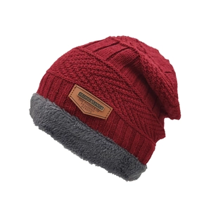 Bonnet en tricot rouge d'hiver avec doublure en fourrure grise et écusson en cuir sur blanc