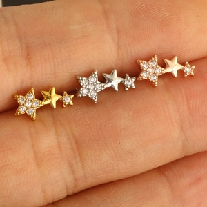 Detailed macro view of triple star stud earrings in gold silver and rose gold finishes