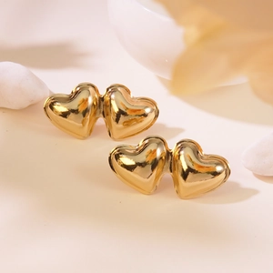 Detail of double heart gold earrings showing high-polished finish and elegant metallic texture