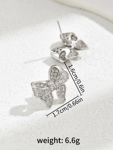 Macro shot of silver bow earrings with zircon stones and product dimension labels