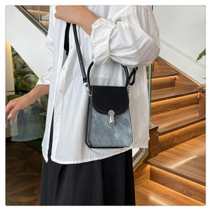 Fashionable black and grey crossbody bag worn by a model in a modern interior setting