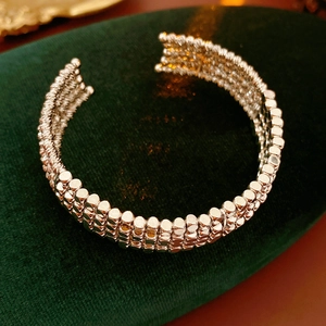 Gros plan sur un bracelet manchette multicouche à perles argentées sur velours vert