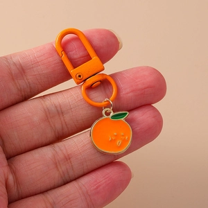 Detailed view of an orange-painted metal keychain featuring a cute cartoon orange pendant
