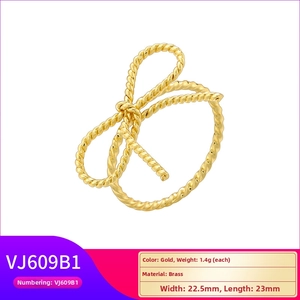 Detail of gold bow ring featuring twisted rope texture and polished brass finish