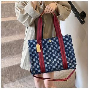 Detail of blue plaid tweed tote bag featuring red straps and gold flower hardware