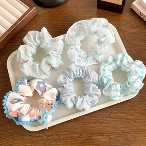 Close-up of five assorted floral and patterned lace scrunchies on a white tray