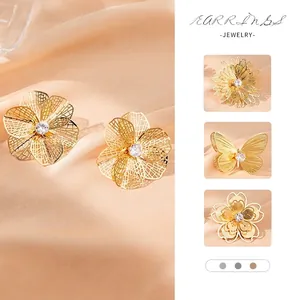 Exquisite hollow gold flower earrings with central white zircon on soft silk background