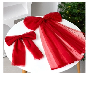 Macro detail of red organza Christmas bows on a white table with festive lights
