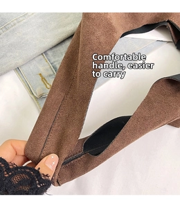 Close-up of brown suede bag handle with reinforced stitching and wide strap detail