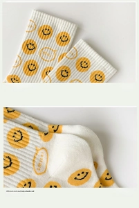 Detail of ribbed cuff and 3D heel design on white socks with yellow smile patterns
