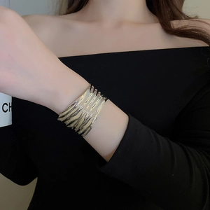Close-up of wide silver open cuff bracelet with irregular wave texture on model wrist