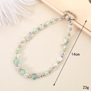 Beaded butterfly floral phone charm with green crystals and pearls on beige tray