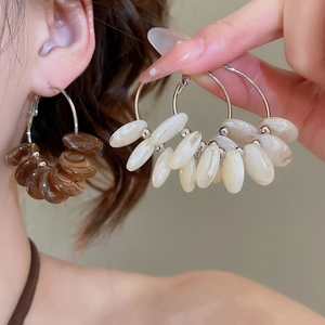 Detail of silver needle resin hoop earrings with brown and cream irregular beads