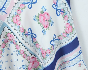 Détail de l'imprimé roses roses et nœuds bleus sur robe d'été en satin fluide