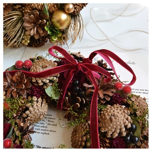 Close-up of handmade Christmas wreath with pine cones, dried roses and velvet bow