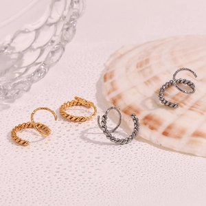 Close-up of twisted helix design earrings in gold and silver finish with water drops