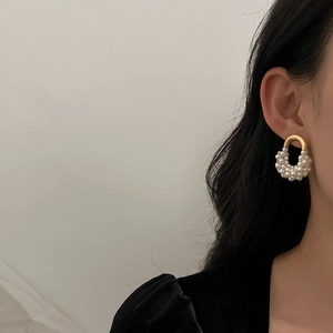 Détail d'élégantes créoles dorées en U avec des perles blanches brillantes sur un mannequin