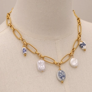 Gold chain necklace with blue floral ceramic heart and baroque pearls on mannequin