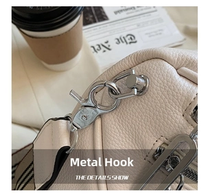 Detailed macro of silver metal hook and pebble grain leather on beige crossbody chest bag