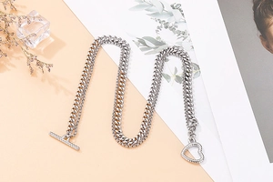 Detail of silver double-layer necklace featuring a stylish heart pendant and OT toggle clasp