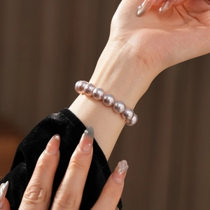 Close-up of elegant purple freshwater pearl bracelet worn with a black velvet sleeve