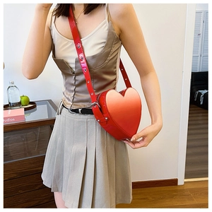 Détail du sac à bandoulière rouge en forme de cœur en similicuir brillant avec œillets