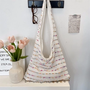 Detail of white crochet tote bag featuring colorful stripes and shell fringe accents